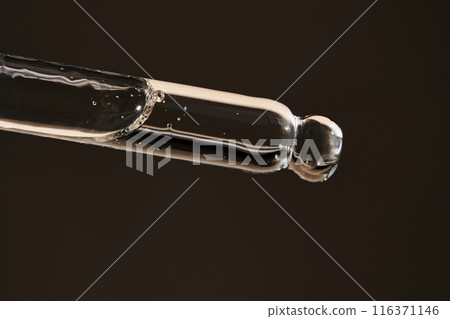 Pipette with serum on a dark beige background. Pipette with serum on a dark beige background. 116371146