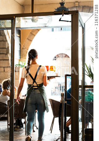 Waitress serving beers with tray on the bar terrace. Vertical 116371288