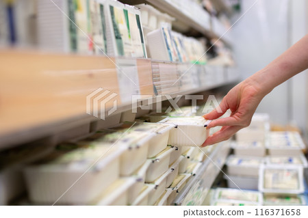 Woman's hand choosing tofu in a supermarket Woman's hand choosing tofu in a supermarket 116371658