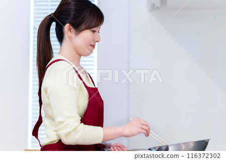 A middle-aged woman wearing an apron cooking A middle-aged woman wearing an apron cooking 116372302