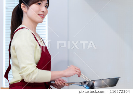 穿著圍裙煮飯的中年婦女 116372304