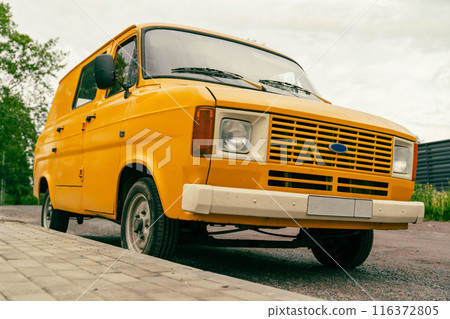 A yellow van is parked on a sidewalk in a city setting A yellow van is parked on a sidewalk in a city setting 116372805