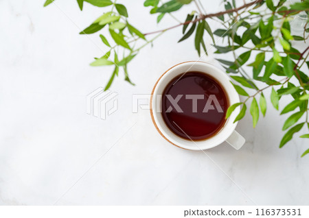 A cup of tea on a light marble background with green branches close-up. Spring women's concept.  116373531