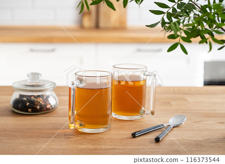 Two cups of tea with dry herbal flowers on a wooden countertop against the background Two cups of tea with dry herbal flowers on a wooden countertop against the background 116373544