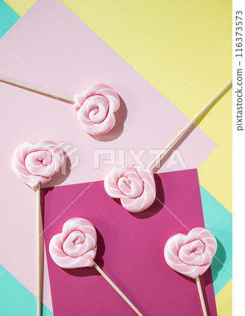 Pink lollipops in the shape of hearts on a color background. Pop art concept. Top view  116373573