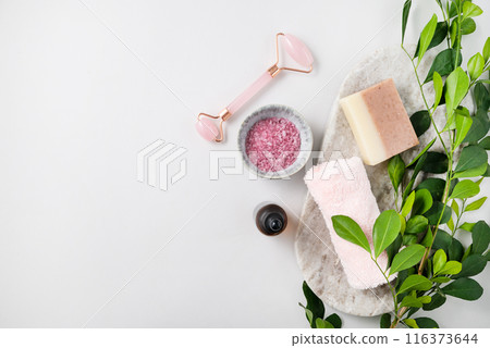 Concept flat lay of facial and body care cosmetics with pink sea salt, soap, massager, towel  116373644