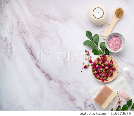 flat lay with organic sea salt with dried rose flowers, soap, candle, brush and gua sha  116373679