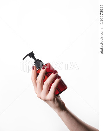 A woman's hand holds a bottle of cosmetics with soap, sanitizer, creme or lotion for face and body A woman's hand holds a bottle of cosmetics with soap, sanitizer, creme or lotion for face and body 116373935