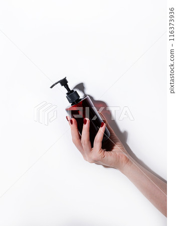 A woman's hand holds a bottle of cosmetics with soap, sanitizer, creme or lotion for face and body A woman's hand holds a bottle of cosmetics with soap, sanitizer, creme or lotion for face and body 116373936