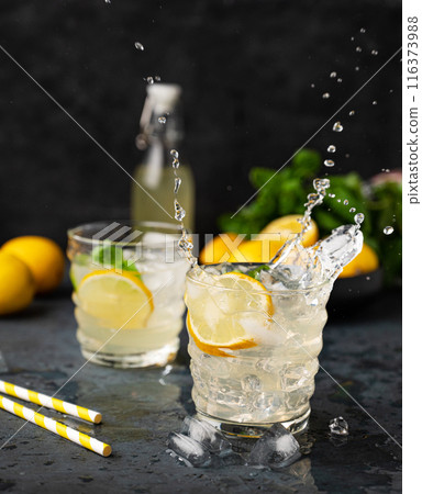 Two glasses of Lemonade drink with fresh lemon and splashes. Refreshing cocktails with lemons Two glasses of Lemonade drink with fresh lemon and splashes. Refreshing cocktails with lemons 116373988