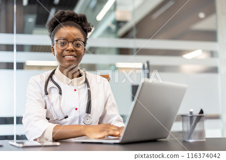 Female doctor wearing white coat and stethoscope working on laptop in modern office. Professional healthcare worker focusing on patient records or medical research. Female doctor wearing white coat and stethoscope working on laptop in modern office. Professional healthcare worker focusing on patient records or medical research. 116374042