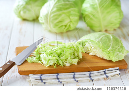 Whole and sliced fresh green cabbage on a white wooden table. Whole and sliced fresh green cabbage on a white wooden table. 116374816