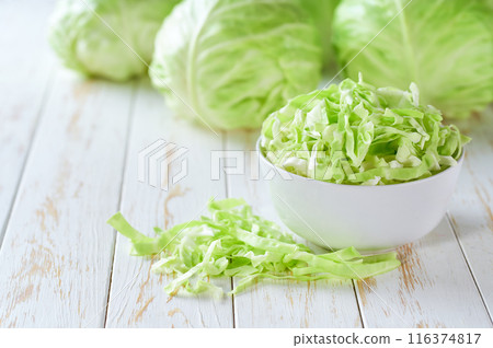 shredded cabbage in a ceramic bowl on a white wooden table. shredded cabbage in a ceramic bowl on a white wooden table. 116374817