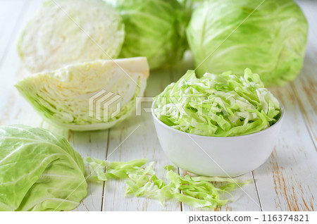 sliced fresh green cabbage in a ceramic bowl on a white wooden table. sliced fresh green cabbage in a ceramic bowl on a white wooden table. 116374821
