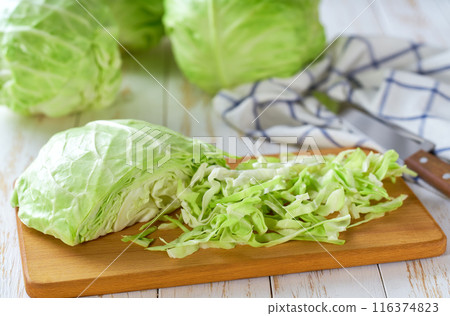 Whole and sliced fresh green cabbage on a white wooden table. 116374823