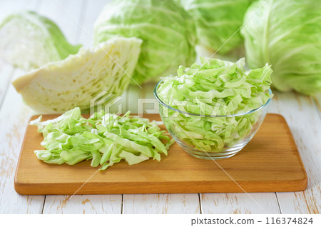 shredded cabbage in a clear glass bowl on a white wooden table. 116374824