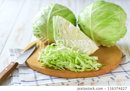 Whole and shredded cabbage on a cutting board. Whole and shredded cabbage on a cutting board. 116374827