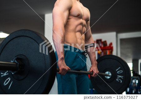A muscular bodybuilder trains with a barbell in a gym 116375027