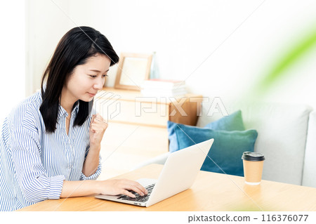 A woman who plays a personal computer in the living room A woman who plays a personal computer in the living room 116376077