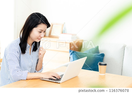 A woman who plays a personal computer in the living room A woman who plays a personal computer in the living room 116376078