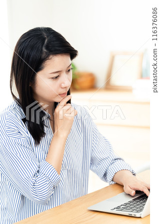 A woman who plays a personal computer in the living room A woman who plays a personal computer in the living room 116376086