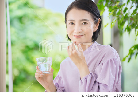 微笑的中年婦女在客廳喝藥 116376303