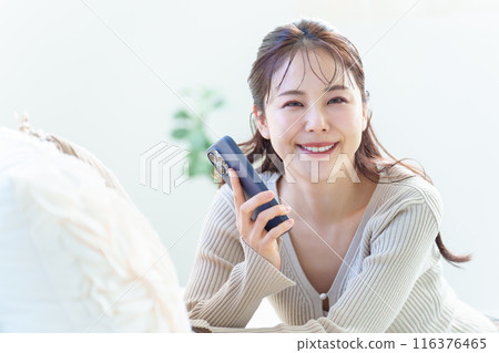 一個女人在客廳裡使用智能手機 一個女人在客廳裡使用智能手機 116376465