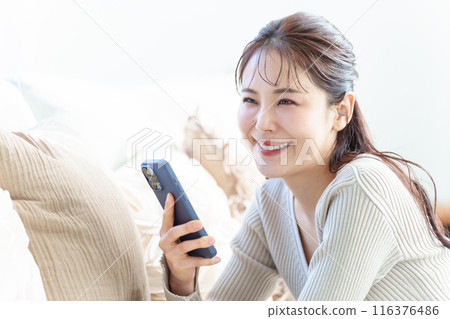 一個女人在客廳裡使用智能手機 116376486