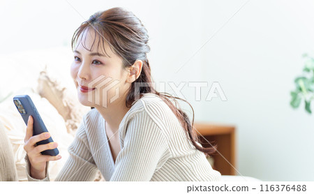 一個女人在客廳裡使用智能手機 一個女人在客廳裡使用智能手機 116376488