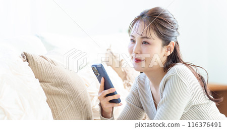 A woman using a smartphone in the living room 116376491
