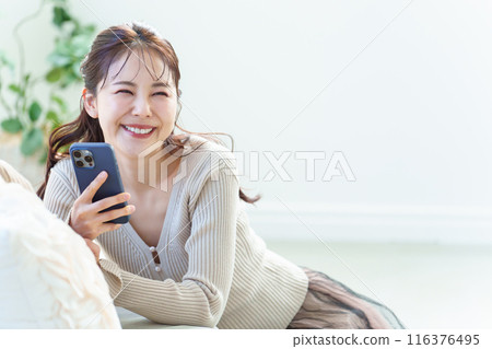 A woman using a smartphone in the living room 116376495