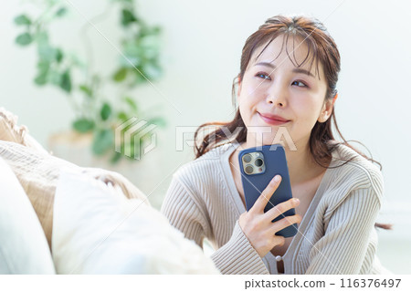 A woman using a smartphone in the living room 116376497