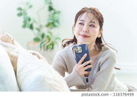 A woman using a smartphone in the living room 116376499