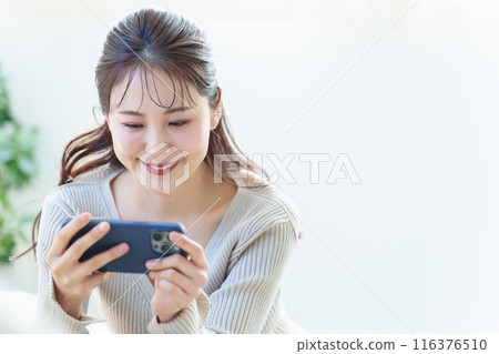 一個女人在客廳裡使用智能手機 一個女人在客廳裡使用智能手機 116376510