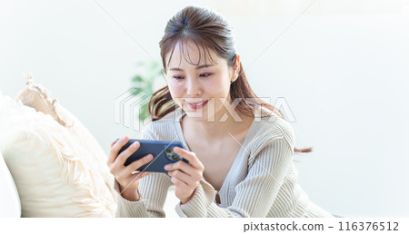 一個女人在客廳裡使用智能手機 一個女人在客廳裡使用智能手機 116376512