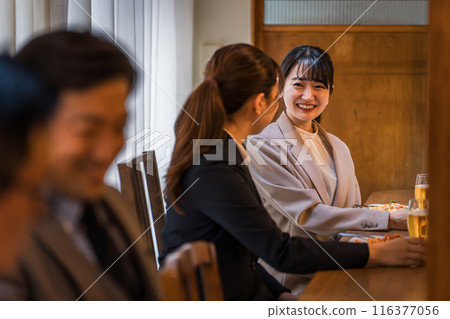 A businesswoman happily drinking with her subordinate at the counter of an izakaya/bar 116377056