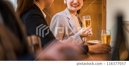 A businesswoman happily drinking with her subordinate at the counter of an izakaya/bar 116377057