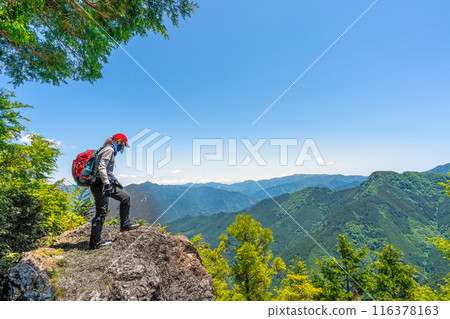 Climber peering down a dangerous cliff 116378163