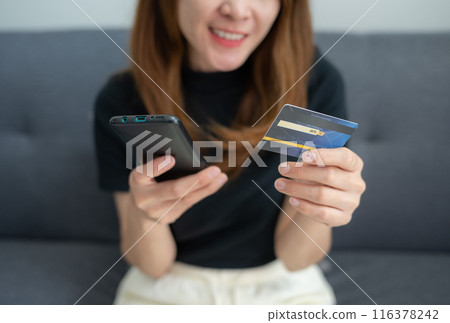 Cropped shot view of woman using credit card for shopping online on mobile phone applications. Cropped shot view of woman using credit card for shopping online on mobile phone applications. 116378242