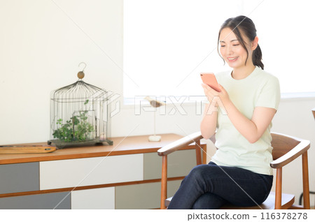 一個女人坐在椅子上操作智能手機 116378278