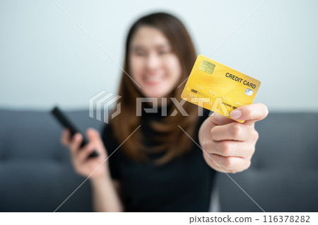 Asian woman showing her credit card for shopping online on mobile phone applications. Asian woman showing her credit card for shopping online on mobile phone applications. 116378282