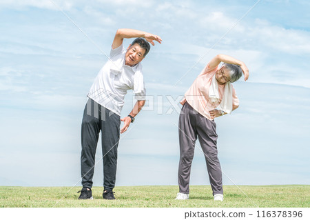 Elderly couple doing radio exercises, stretching, training, and flexible exercises in the park 116378396