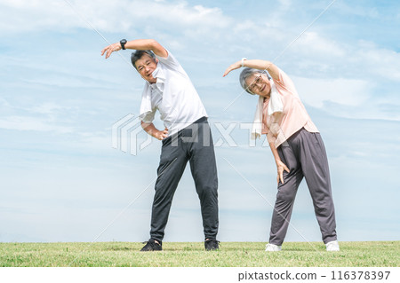 Elderly couple doing radio exercises, stretching, training, and flexible exercises in the park 116378397