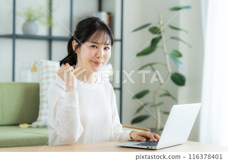 使用一台電腦在客廳裡的年輕女子 使用一台電腦在客廳裡的年輕女子 116378401