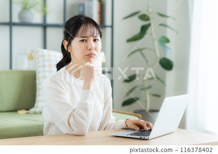 Young woman using a computer in the living room Young woman using a computer in the living room 116378402