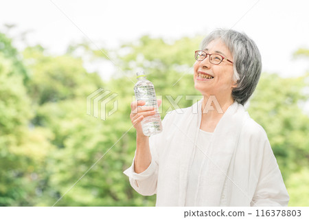 Senior Asian woman drinking mineral water in the park/forest 116378803