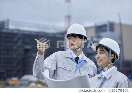 A businessman and a businesswoman inspecting a construction site 116379191