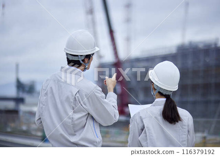 A businessman and a businesswoman inspecting a construction site 116379192