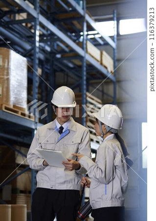 Men and women in work clothes having a meeting at a factory 116379213