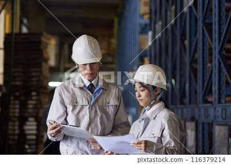 Men and women in work clothes having a meeting at a factory 116379214